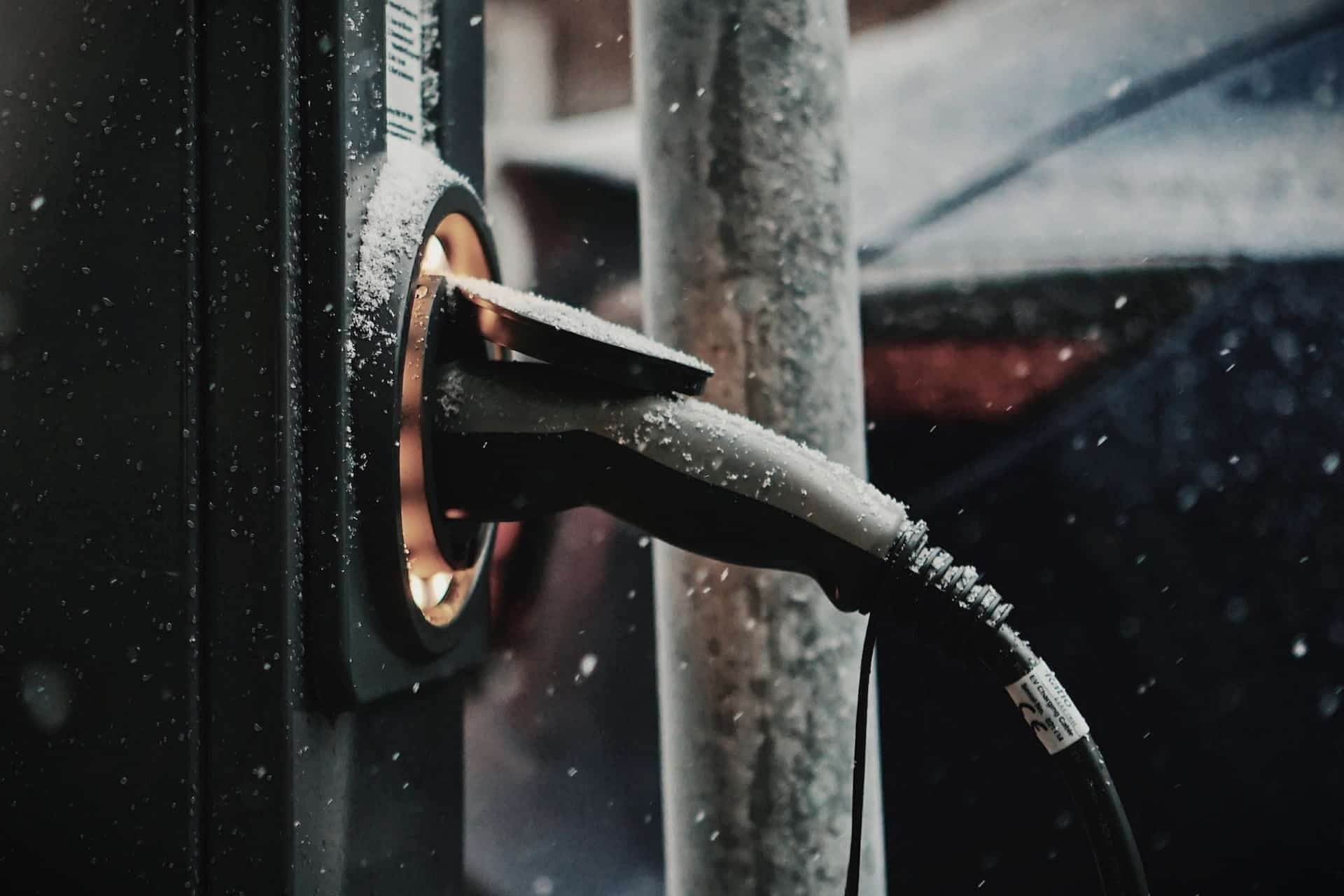 an ev is plugged into a charger in the snow