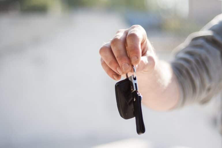 A person's arm extended holding a set of car keys.