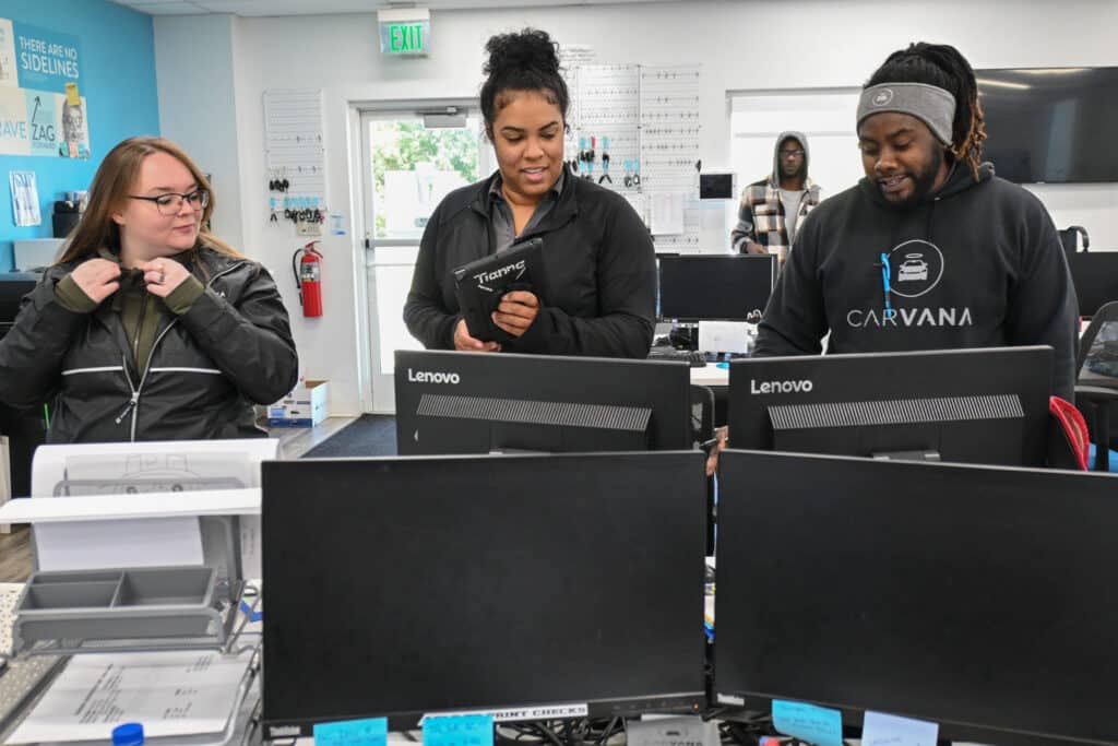 Carvana employees taking care of behind-the-scenes work to ready vehicles for the car vending machine.