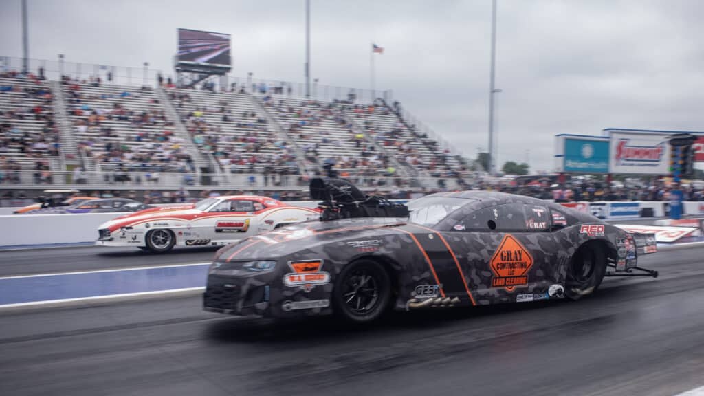 nhra drag racers in motion. a black car is in the foreground