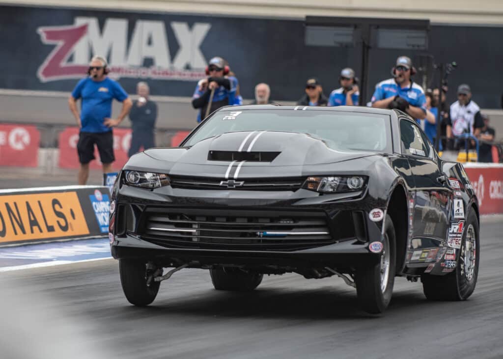 a black car racing at the circle k nhra four-wide nationals at zmax speedway