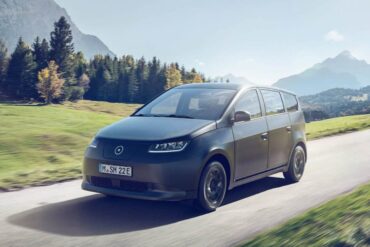 sono motors sion solar-powered ev driving on a road with mountains in the backdrop