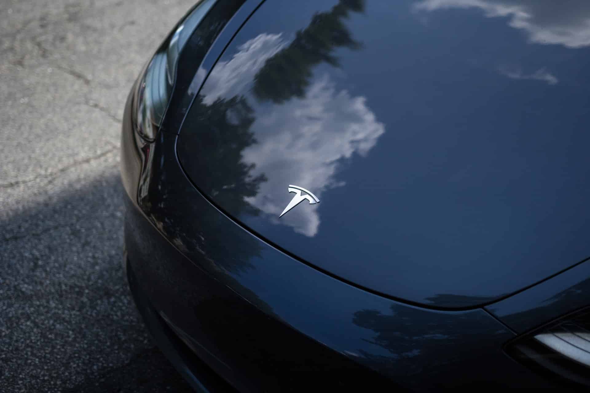 the hood of a black tesla with a chrome tesla logo