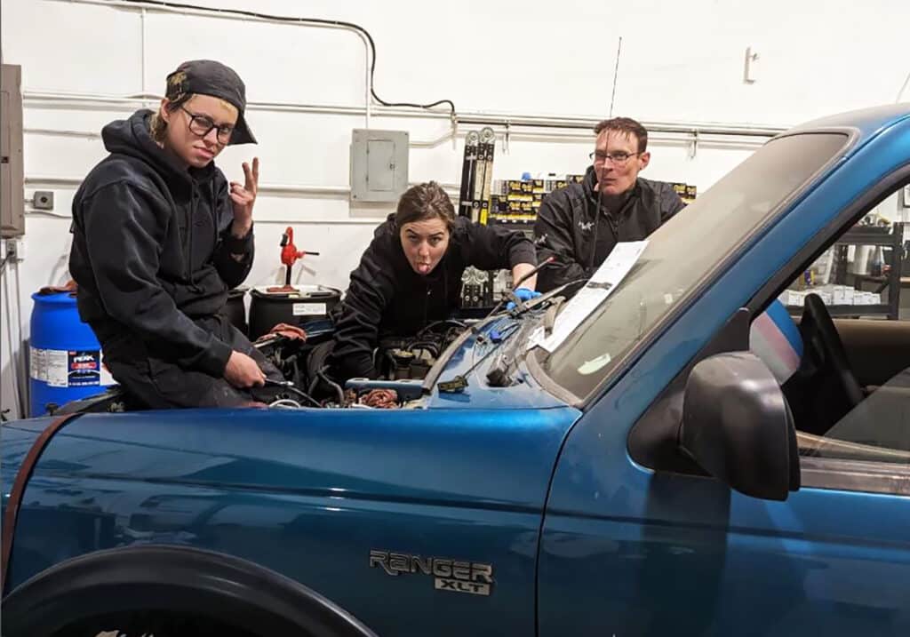 cc haug and two workers at good judy garage stand behind a blue ford pickup truck